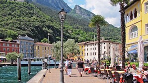 A waterfront promenade with outdoor seating, a historic building, and a mountain backdrop. - Villa im Grünen in Riva del Garda mit Terrasse by Interhome (Riva del Garda)