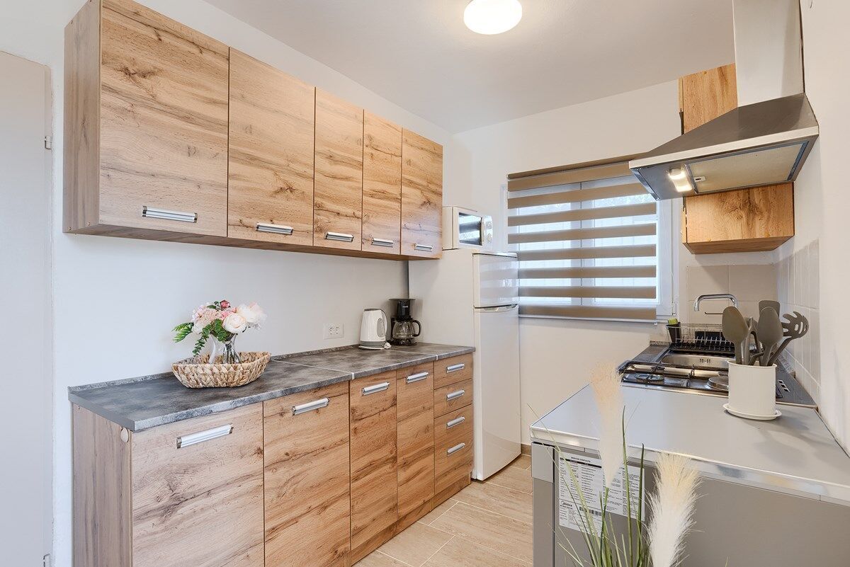 Une cuisine moderne avec des meubles en bois, un four à micro-ondes encastré et une hotte de cuisine en acier inoxydable.