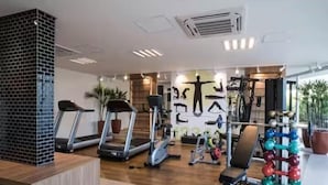 Un gimnasio moderno con cintas de correr, una máquina de remo y una zona de levantamiento de pesas.