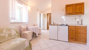 A compact kitchen with wooden cabinets, a small dining table, and a sofa. - Apartments and Room Vjera (76011-A1) - Medulin (Medulin)