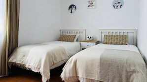 A bedroom with two single beds, a nightstand, and a wall with decorative items. - Family-friendly house with Garden, 4 Minutes from the Beach (Cambrils)