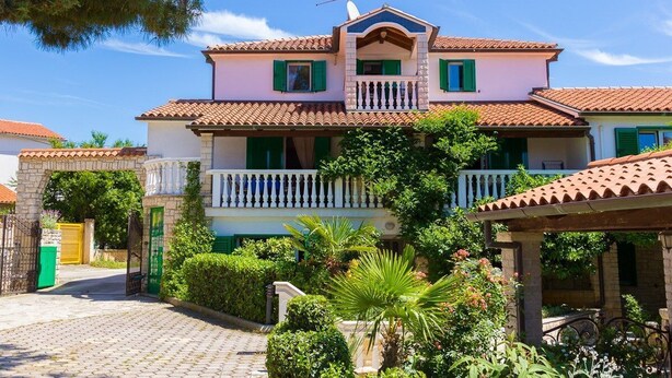 A two-story house with a balcony, a tiled roof, and a garden with various plants. - Apartments and Room Vjera (76011-A5) - Medulin (Medulin)