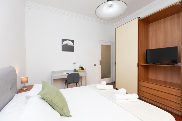 Ein Hotelzimmer mit Bett, Schreibtisch, Stuhl, Fernseher und Kleiderschrank.