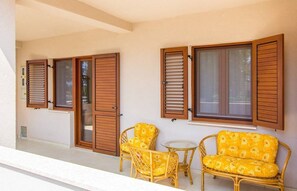Un balcon agrémenté de meubles en osier et de volets en bois.