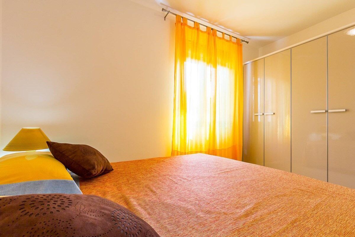 A bedroom with a bed, a wardrobe, and curtains.