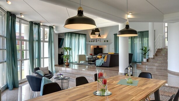 Een ruime woonruimte met een houten eettafel, zwarte stoelen en hanglampen.