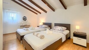 Una camera d'albergo con due letti, un comodino, una lampada e una finestra con tende.