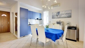 Una cucina moderna con mobili blu, un tavolo da pranzo con sedie e un quadro appeso al muro.