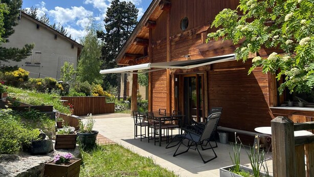 A wooden cabin with a patio, outdoor seating, and a garden. - A B&B in the heart of Chalet Mitja, calm and well-being guaranteed! (La Cabanasse)