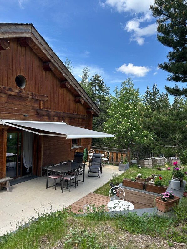 A wooden building with a patio area, outdoor seating, and a garden.