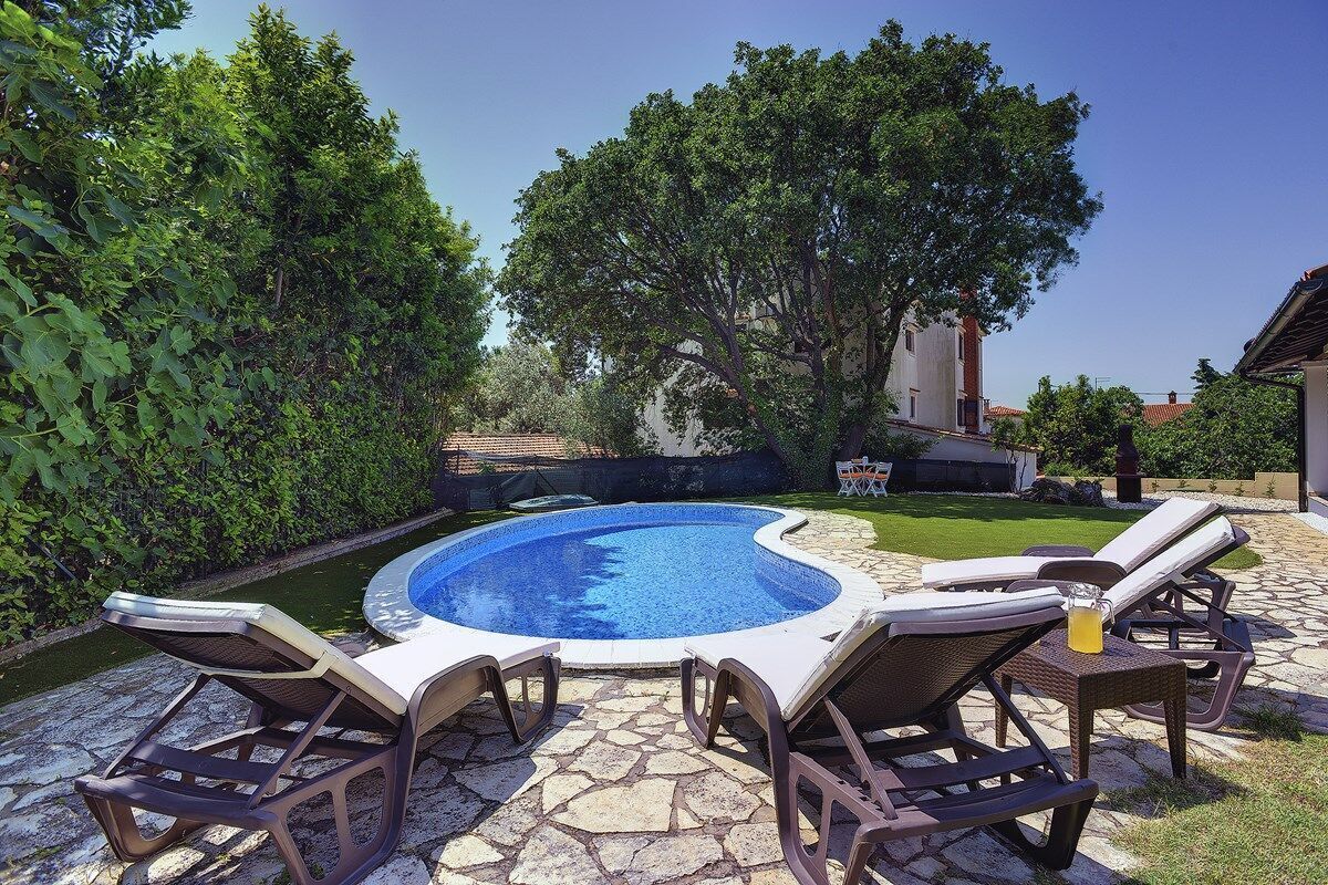 Une piscine avec des chaises longues et une terrasse en pierre.