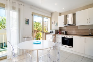 A modern kitchen with a dining area, white cabinets, a microwave, and a stove. - “Miramar 2nd” Apartment with Balcony, Wi-Fi, and Air Conditioning (Cagnes-sur-Mer)