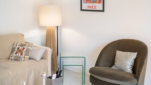 Ein modernes Wohnzimmer mit einer Couch, einem Sessel, einer Stehlampe, einem kleinen Tisch und einem gerahmten Bild an der Wand.