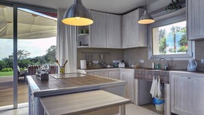 Una cocina moderna con una isla grande, luces colgantes y vistas al exterior.