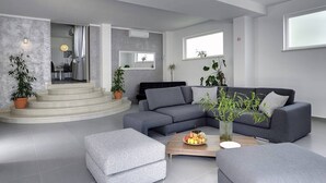 En moderne stue med en grå hjørnesofa, et sofabord med frugt og potteplanter.