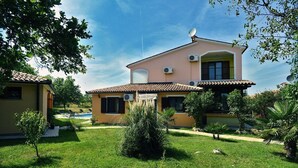 A two-story house with a tiled roof, a satellite dish, and a small garden with grass and shrubs. - Villa Fatima (V3497-K1) - Krnica (Pula) (Krnica (Pula))