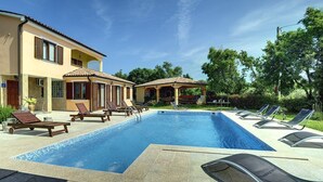 A swimming pool with lounge chairs, a covered seating area, and a building with a tiled roof. - Villa Fatima (V3497-K1) - Krnica (Pula) (Krnica (Pula))