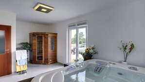 Ein modernes Badezimmer mit einer großen Badewanne, einem Holzschrank und einem Fenster mit Außenblick.