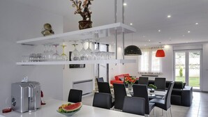Eine moderne Küche mit weißen Schränken, einem eingebauten Backofen und einem Essbereich mit schwarzen Stühlen und einem weißen Tisch.
