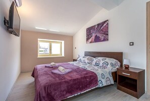 Ein Schlafzimmer mit einem Bett, einem Nachttisch, einer Lampe, einem Fenster und einem Bild an der Wand.