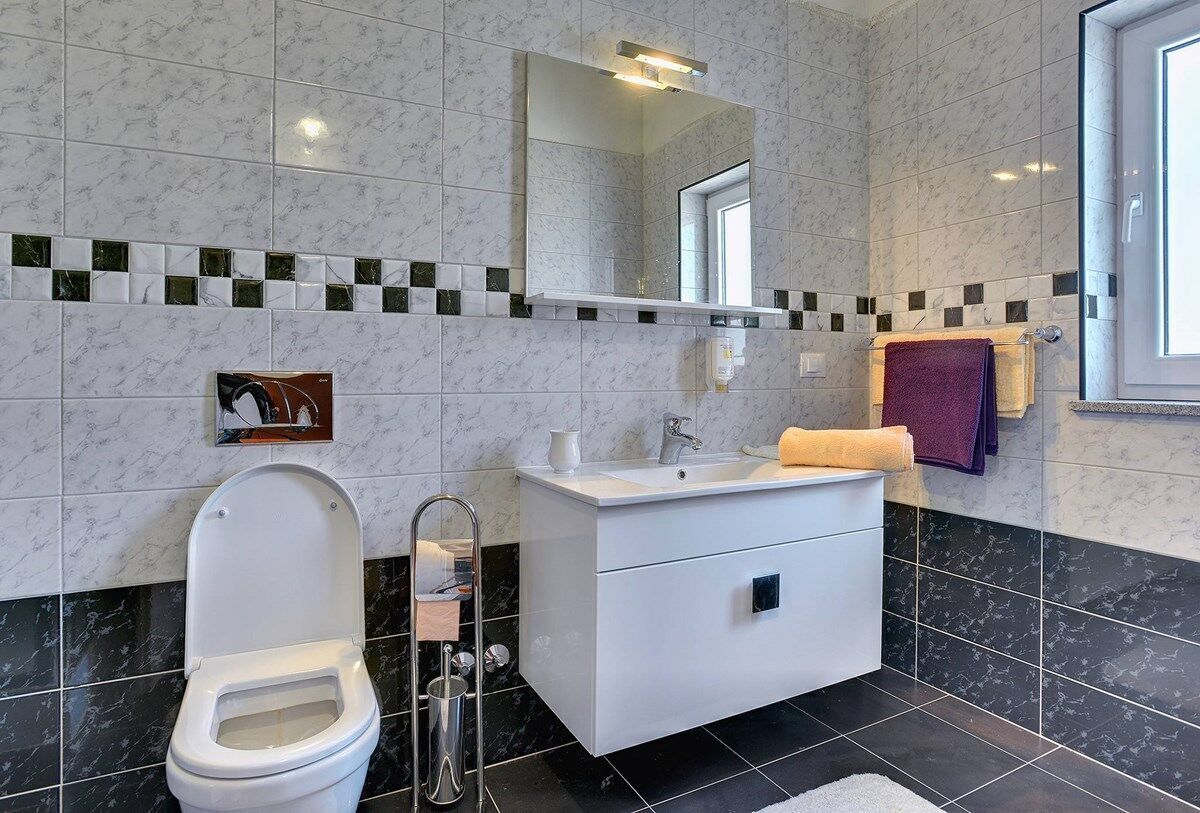A modern bathroom with a toilet, sink, and mirror.