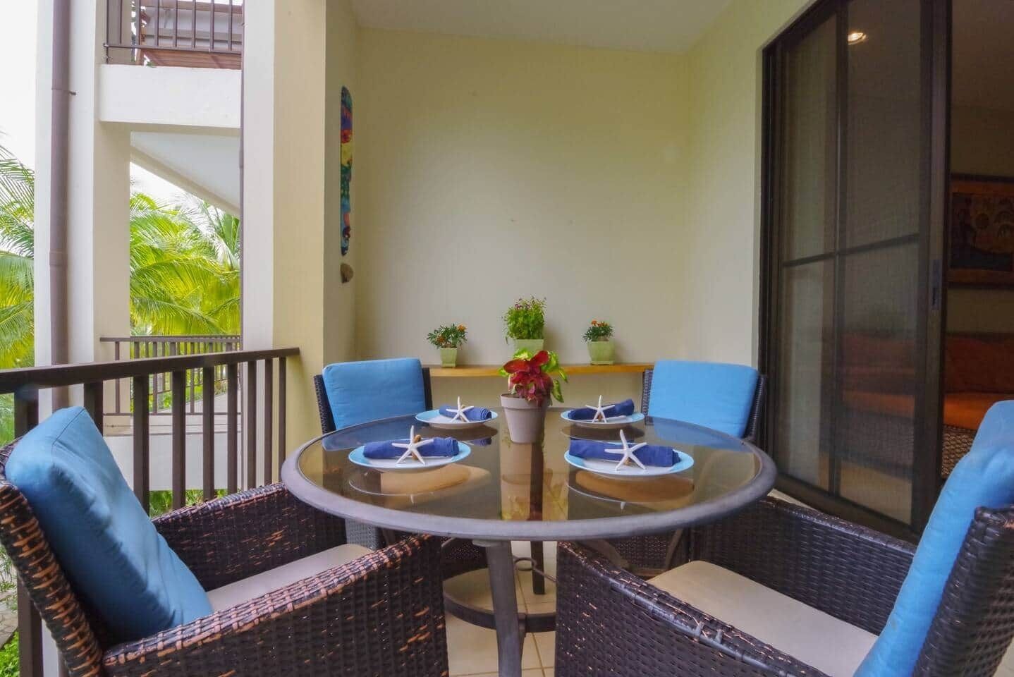 A round glass table with blue cushions and starfish decorations, surrounded by wicker chairs.