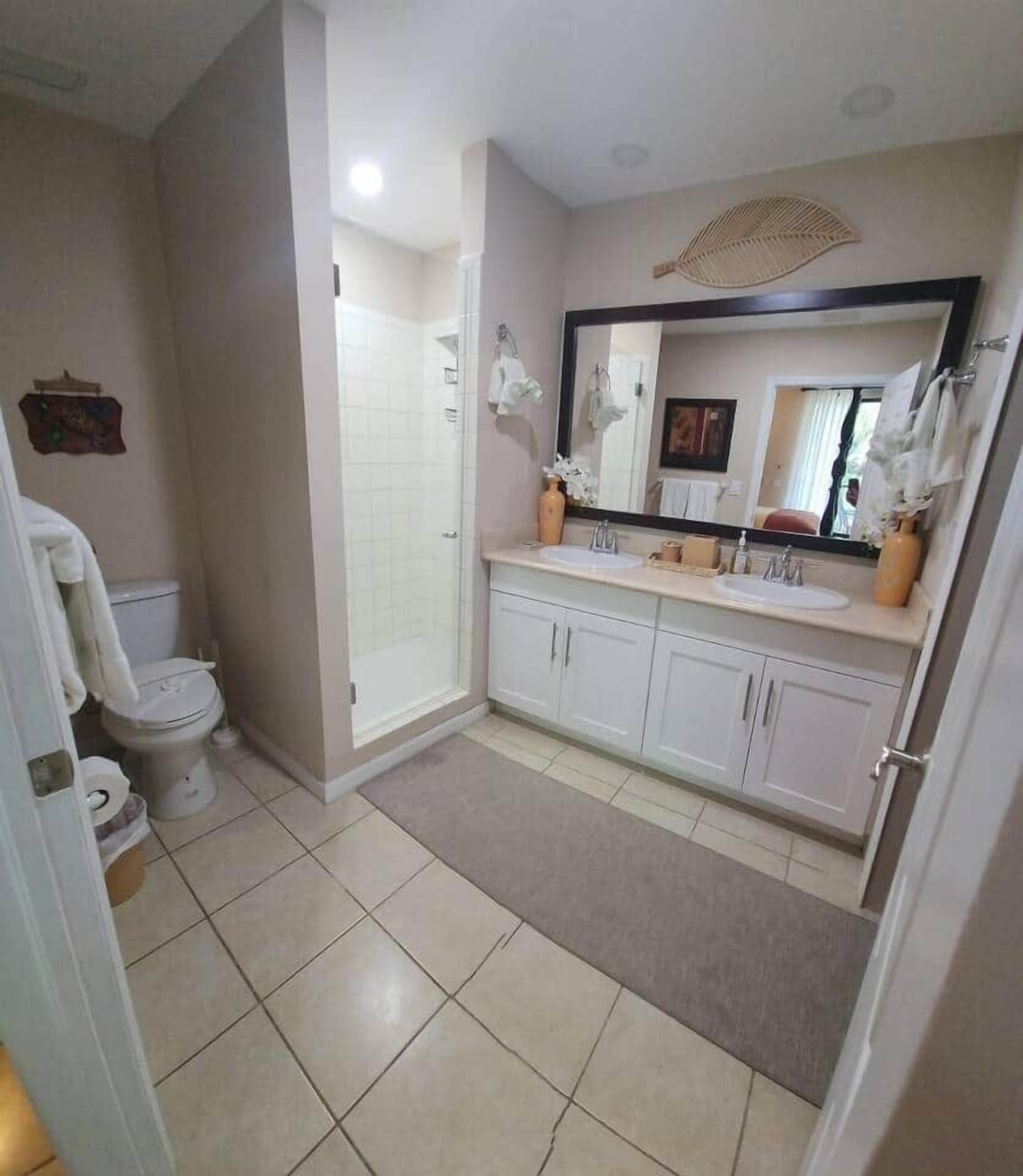 A bathroom with a toilet, shower, sink, and cabinets.
