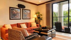 A living room with a sofa, armchair, coffee table, and a view of the outdoors through large windows. - Wake Up in Paradise, Amazing 3BDR Condo Near Beach (Coco)