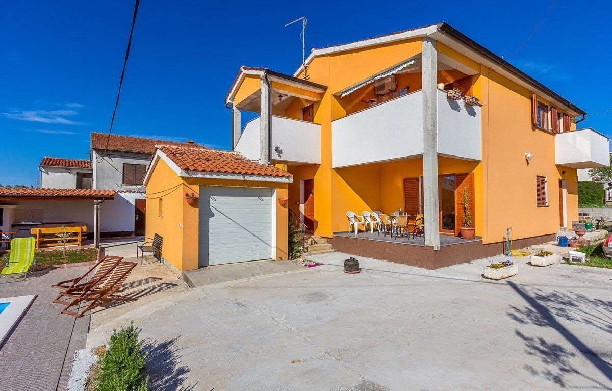 A two-story house with a balcony, a garage, and outdoor seating.