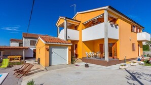 Ein zweistöckiges Haus mit Balkon, Garage und Außenbestuhlung.