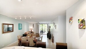 A spacious dining area with a long table and chairs, a ceiling fan, and decorative wall art. - 3 BDR 2 bath Luxurious CONDO, Pool Front (Coco)