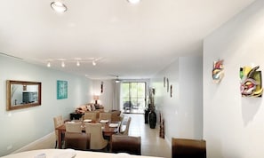 A spacious dining area with a long table and chairs, a ceiling fan, and decorative wall art. - 3 BDR 2 bath Luxurious CONDO, Pool Front (Coco)