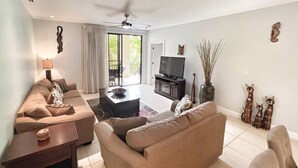 A living room with a sofa, a coffee table, a TV, and decorative items. - 3 BDR 2 bath Luxurious CONDO, Pool Front (Coco)