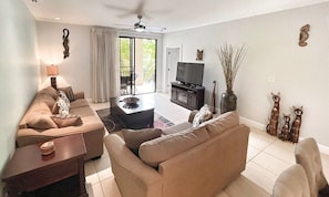 A living room with a sofa, a coffee table, a TV, and decorative items. - 3 BDR 2 bath Luxurious CONDO, Pool Front (Coco)