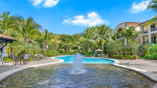 A pool with a water fountain, surrounded by palm trees and lounge chairs. - 3 BDR 2 bath Luxurious CONDO, Pool Front (Coco)