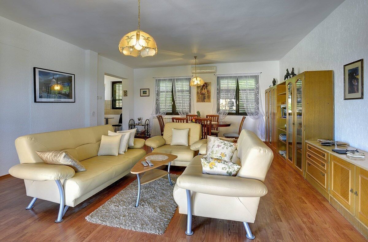 A living room with a beige sofa set, a coffee table, and a dining area with a wooden table and chairs.