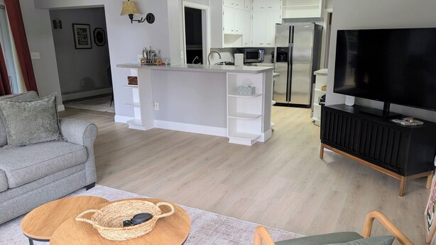 Una sala de estar moderna con un sofá gris, una mesa de centro de madera y un televisor sobre un mueble negro.