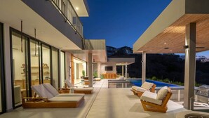 Ein moderner Außenbereich mit Pool, Liegestühlen und einer Holzpergola.