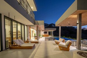 Ein moderner Außenbereich mit Pool, Liegestühlen und einer Holzpergola.