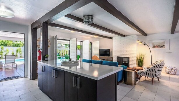 Eine moderne Küche mit dunklen Schränken, einer großen Kochinsel und einer Sitzecke mit blauen Sofas.