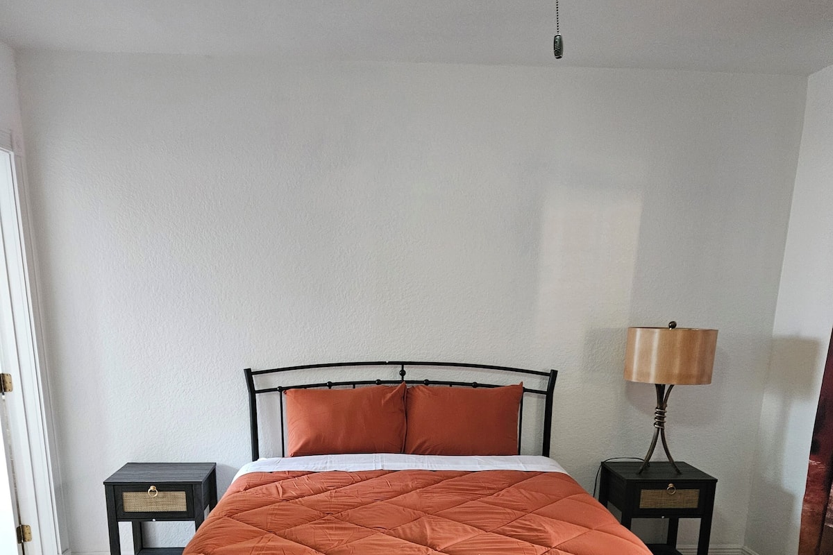 Een slaapkamer met een bed, twee nachtkastjes en een lamp.
