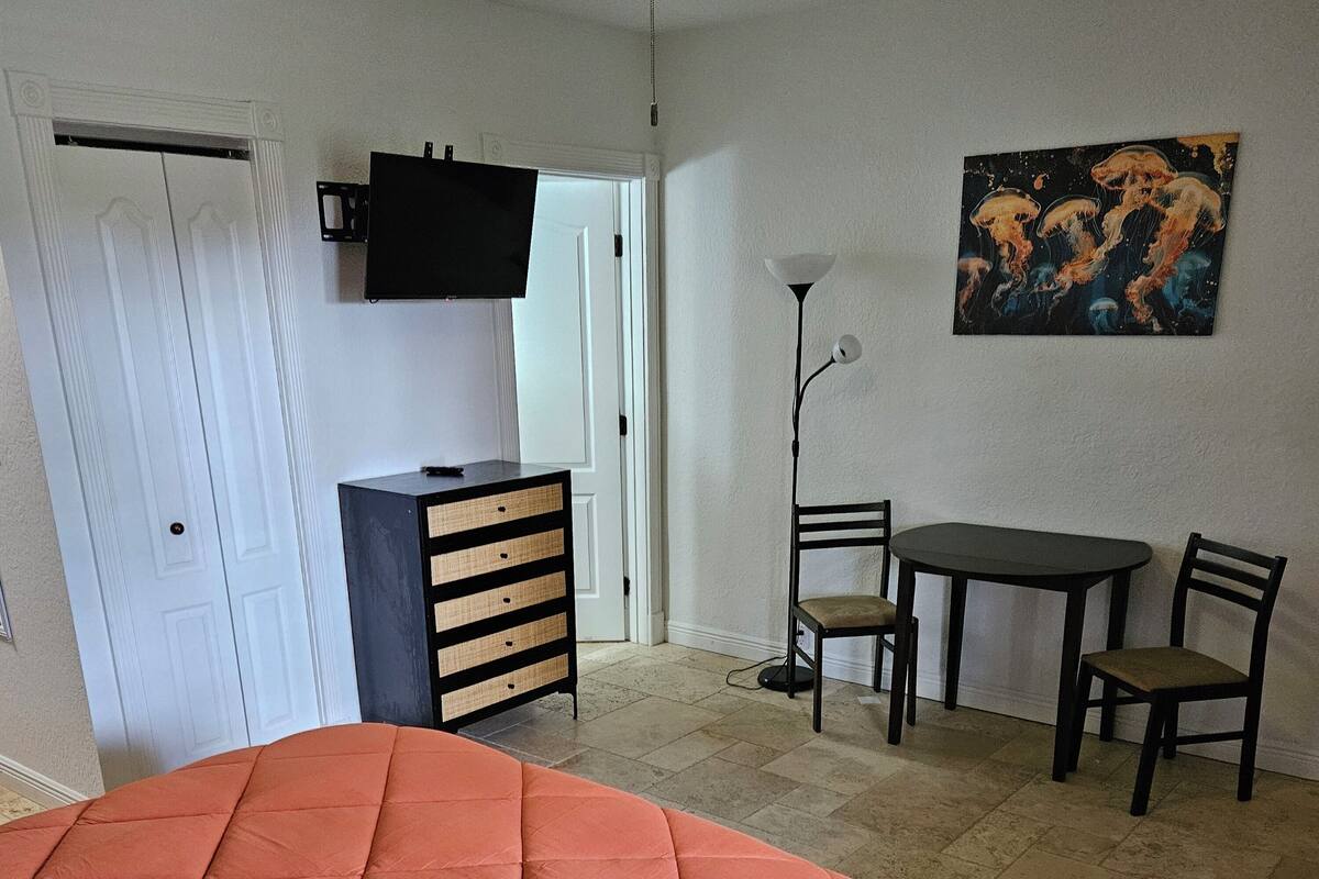Een slaapkamer met een bed, een bureau, een stoel, een kast en een schilderij aan de muur.