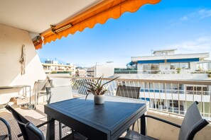 Ein Balkon mit Tisch und Stühlen, einem Blumentopf und Blick auf die umliegenden Gebäude.