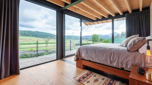 Camera da letto con un'ampia finestra, soffitto in legno e un letto con testiera.