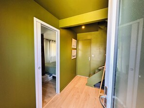 A narrow hallway with wooden flooring, a green door, and a staircase with a wooden handrail. - Les Eléments - Quiet, dunes and sandy beach within walking distance - 6 people (Quend)