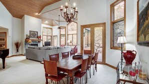 Amplia sala de estar con comedor, chimenea y grandes ventanales con vistas al exterior.