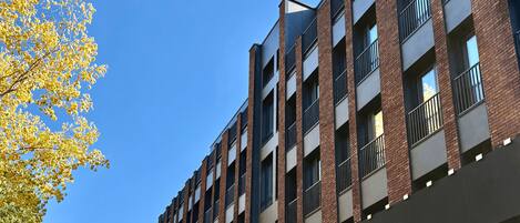 A multi-story building with a modern architectural design, featuring a brick facade and large windows.