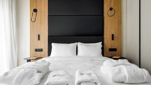 A neatly made bed with white linens and towels, a black upholstered headboard, and wooden paneling on the walls. -  Hayashi Residence (Sofia)