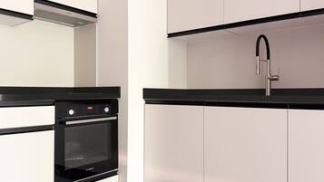 Eine Küche mit Backofen von Bosch, einer schwarzen Arbeitsplatte und weißen Schränken.