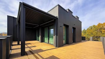Un edificio moderno con techo plano, ventanas amplias y una terraza de madera.